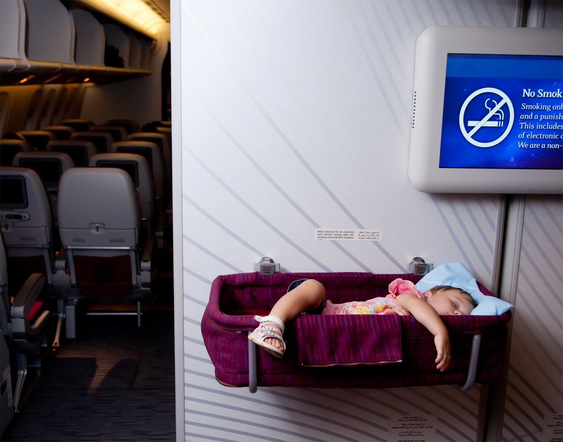 Kind schläft im Stubenwagen in einem Flugzeug